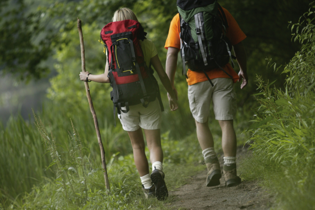 two people with backpacks walking down a trail